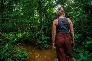 Traveler wading through water along an Amazon jungle trail