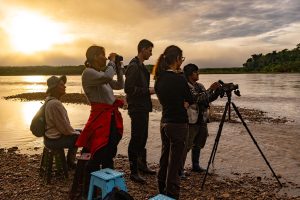 Tourists watching sunset by the river during the Jungle Trail experience